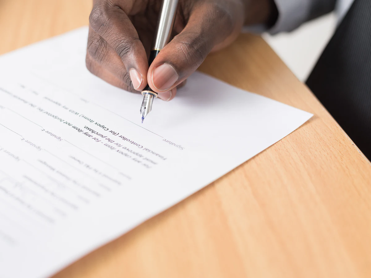 Person signing a document with a pen