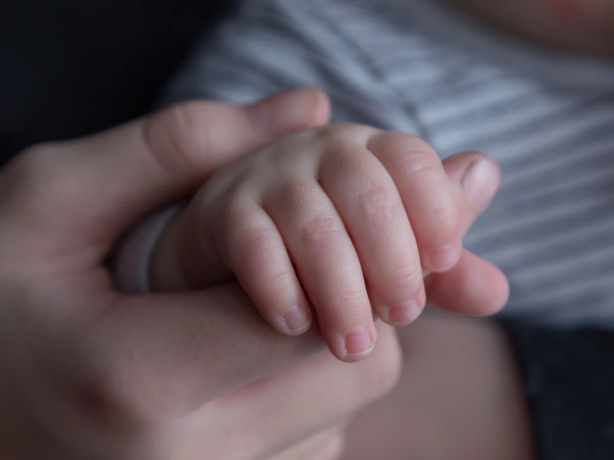 Parent's hand holding a small child's hand