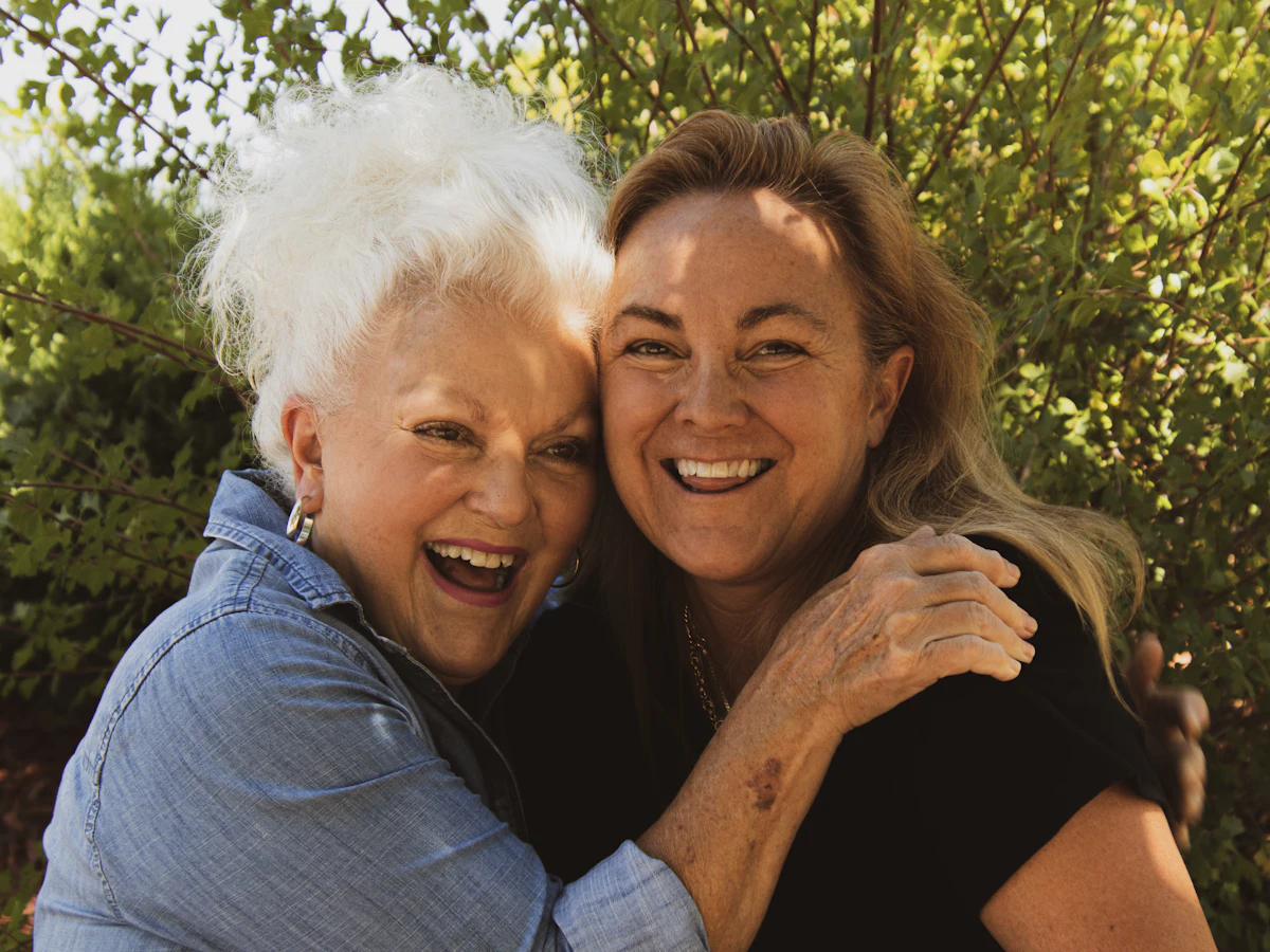 Older mother and adult daughter hugging outdoors