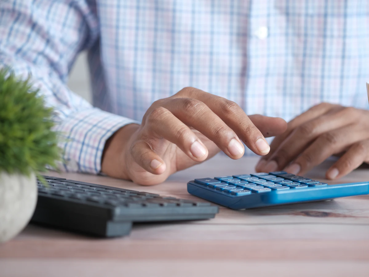 Hands working on a calculator next to paperwork